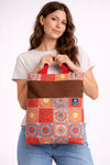 Woman holding a colorful patterned tote bag against a white background